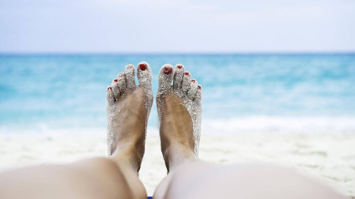 Close up of female legs and feet sunbathing on beach.jpg