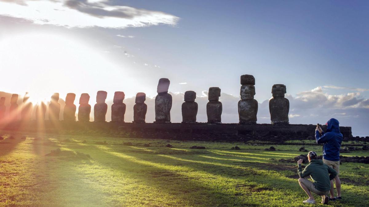 couple photographing back lit Moai statues at Rapa Nui against sky during su.jpg