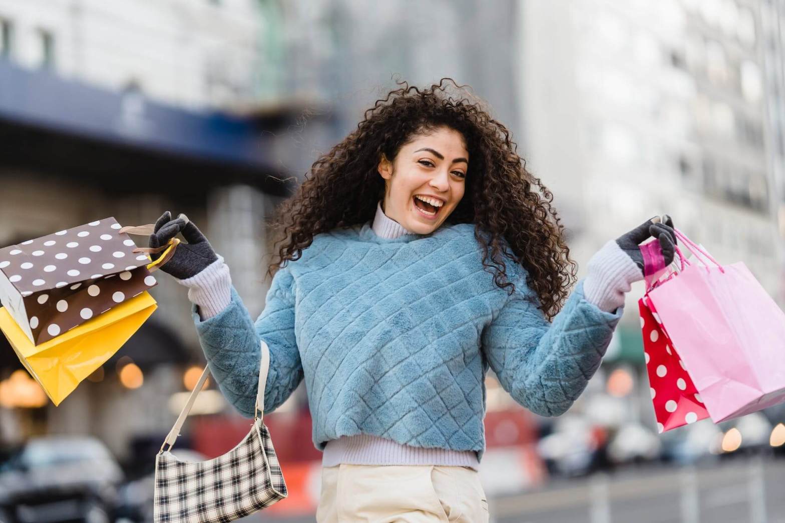 happy ethnic woman demonstrating shopping bags