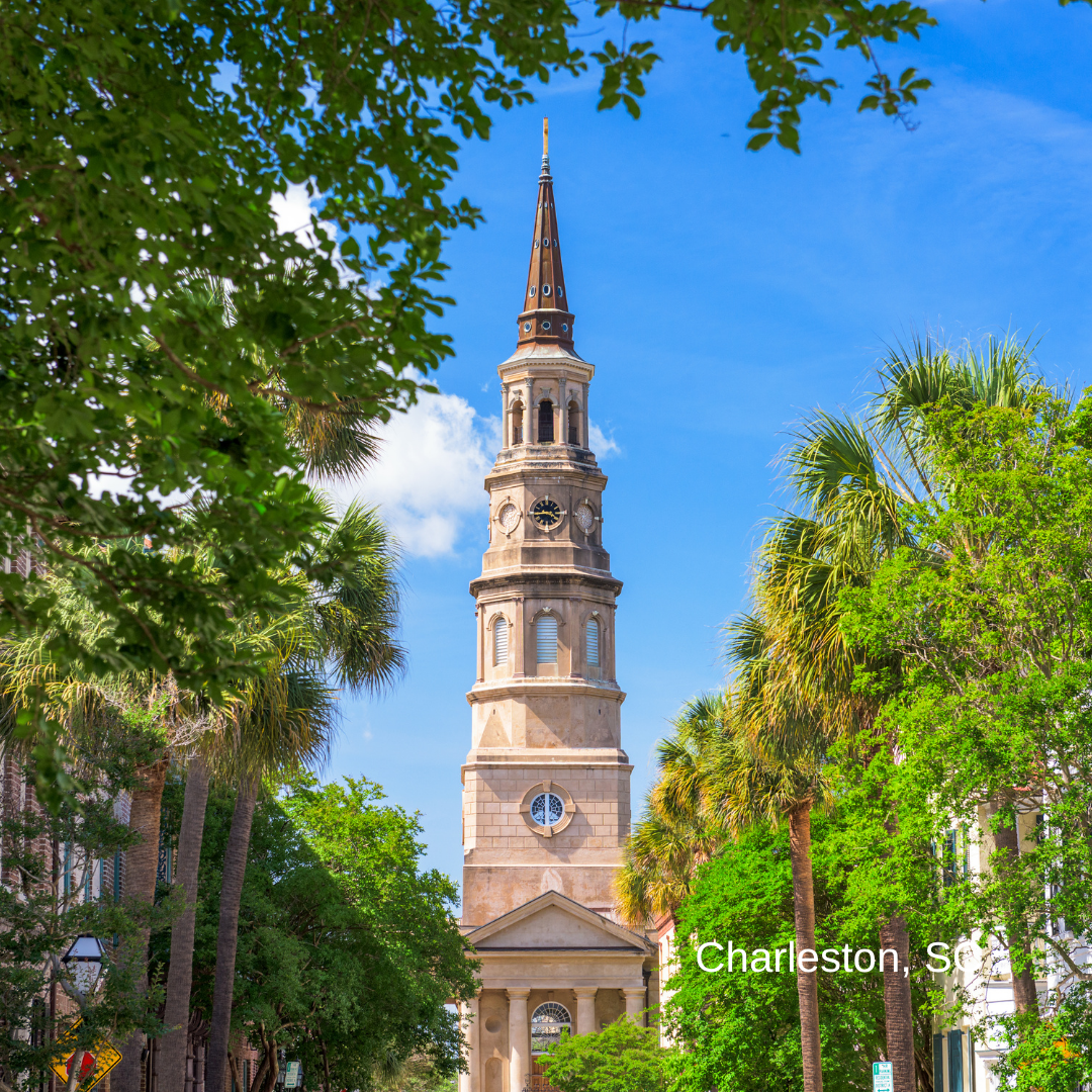 A view of the historic downtown Charleston skyline featuring a prominent church steeple and classic stone architecture along a quiet, misty street.